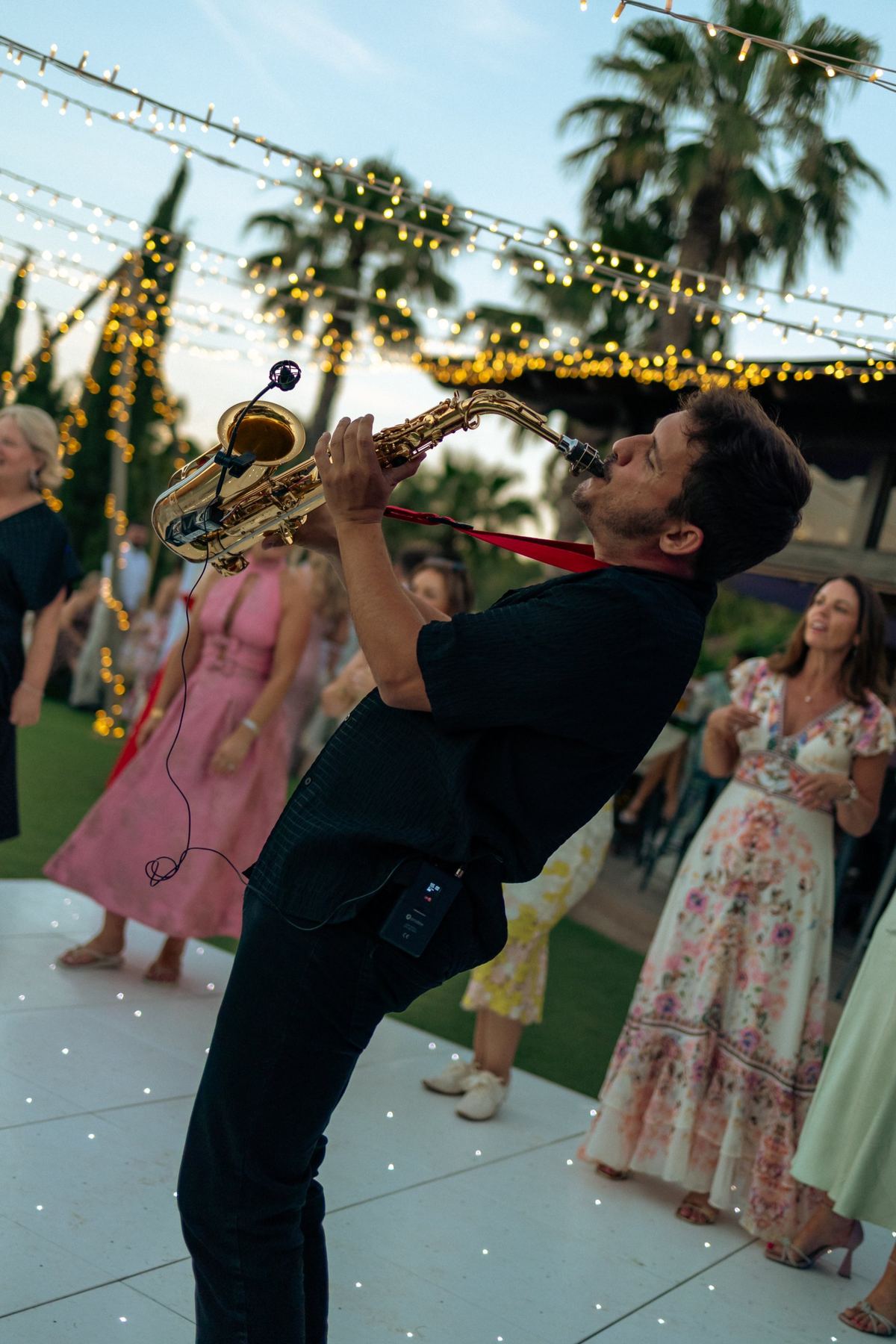 Sax Kid Marbella, saxofonista de Marbella, tocando bajo guirnaldas de luces en un evento al aire libre